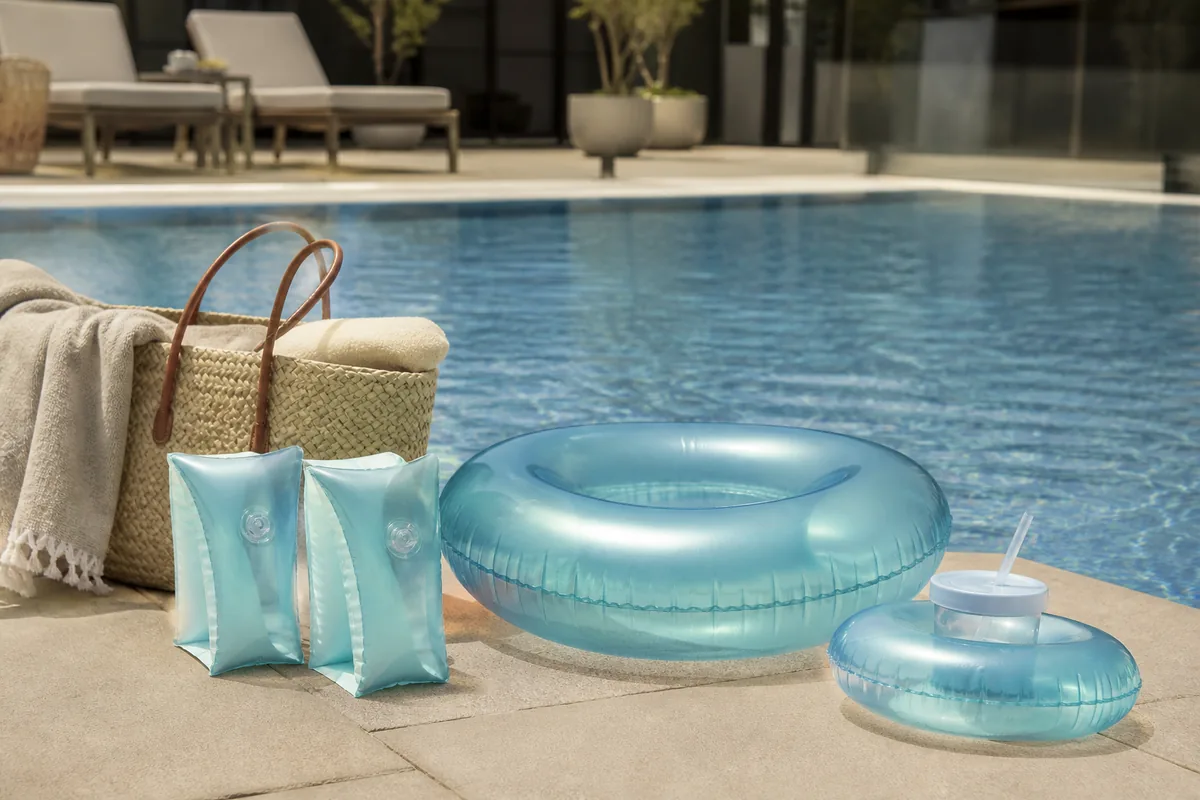 Boias infantis e mini boia porta-copo organizadas à margem de uma piscina