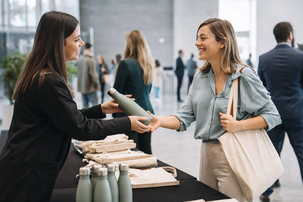 Profissional entrega uma garrafa reutilizável como brinde promocional em um evento corporativo