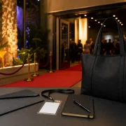 Bolsa, caderno, caneta e credencial em recepção de festival de cinema