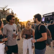 Público em festival de música usando copos e garrafas reutilizáveis diante de um palco