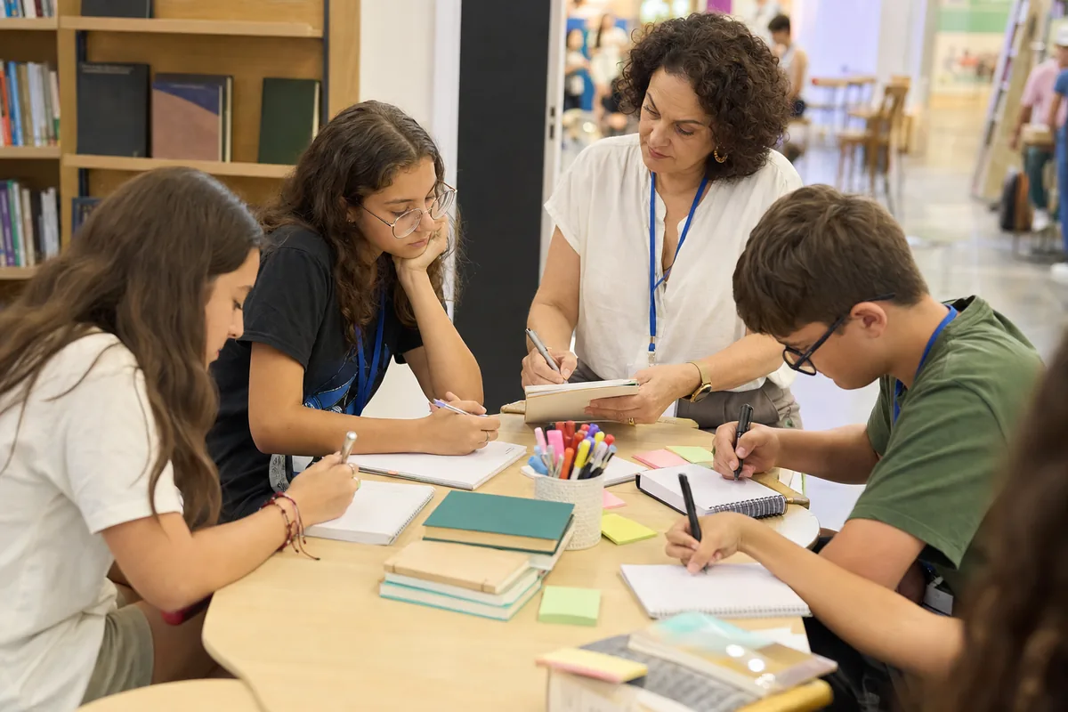 Estudantes e professora usando blocos e canetas em uma oficina literária