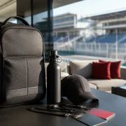 Mochila, garrafa e boné em lounge corporativo com vista para autódromo