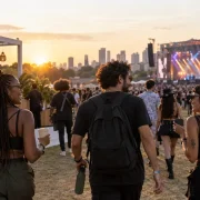Público circulando em festival de música ao ar livre com copos e garrafa reutilizável