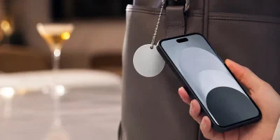 Celular próximo a chaveiro NFC em 3D preso a uma bolsa em ambiente corporativo