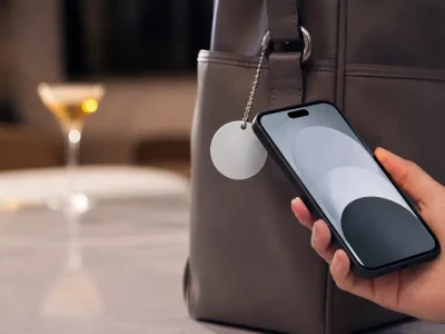 Celular próximo a chaveiro NFC em 3D preso a uma bolsa em ambiente corporativo